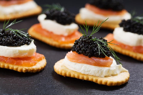 black caviar, salmon, and soft cheese on a cracker