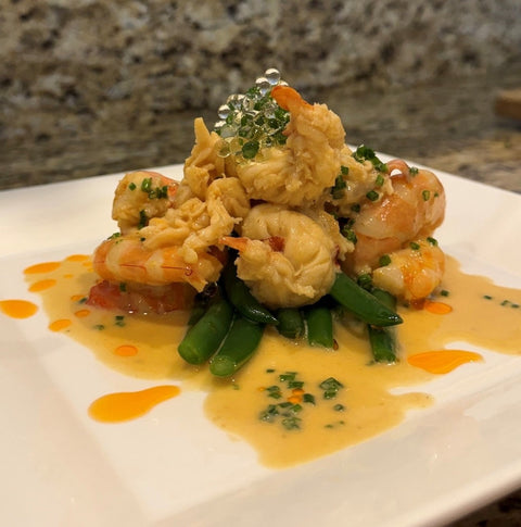 finished dish of lobster with lobster oil and white balsamic pearls arranged on plate