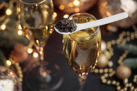 a spoon of caviar balancing on a drink near table holiday decorations