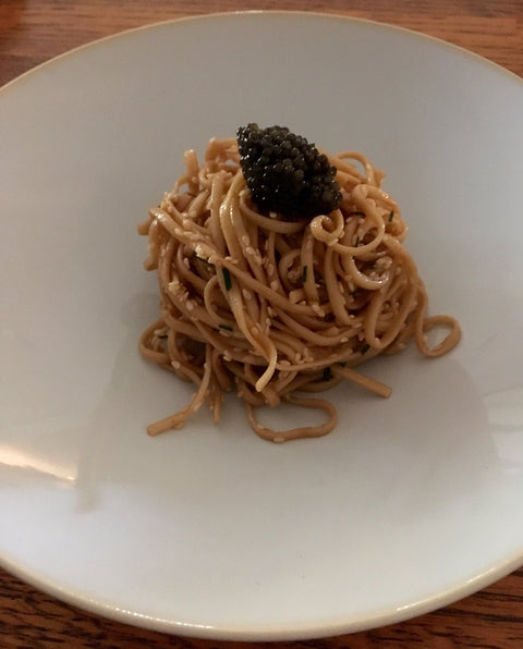 noodles topped with Kaluga caviar and sesame seeds in a white bowl