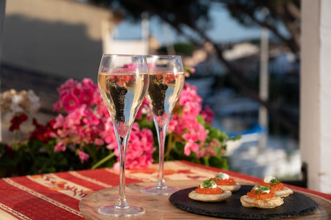cavair topped blinis next to wine glasses on a red table cloth