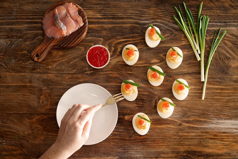 person eating caviar topped deviled eggs with a fork